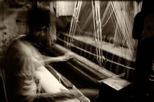 This is a long-exposure image of a man weaving a saree in Varanasi