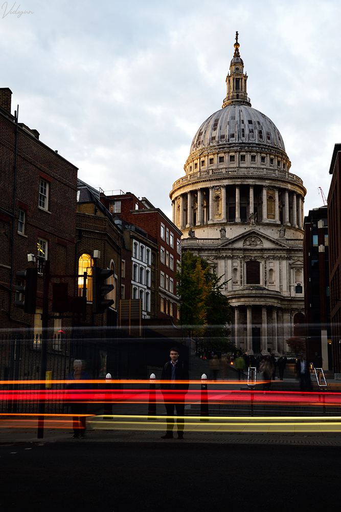 This is an image of St. Pauls Cathedral in London with a light trail in the foreground of many vehicles