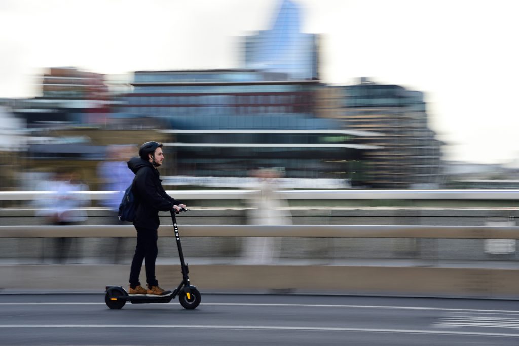 This is a panning of image of a person riding a scooter on the iconic London bridge, in London