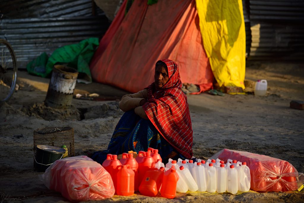 A warm image of a woman standing beside many cans, with a orange tent in the background